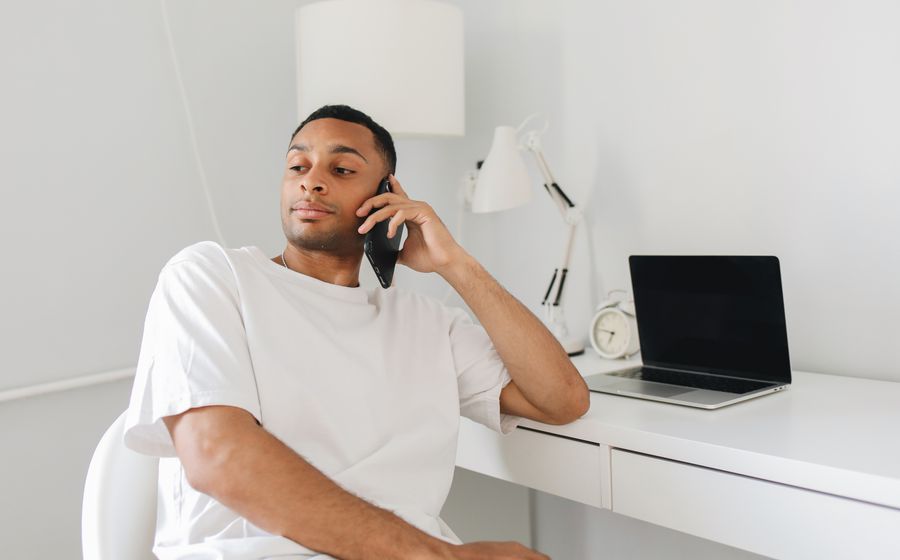 A man on a phone call at his desk at home