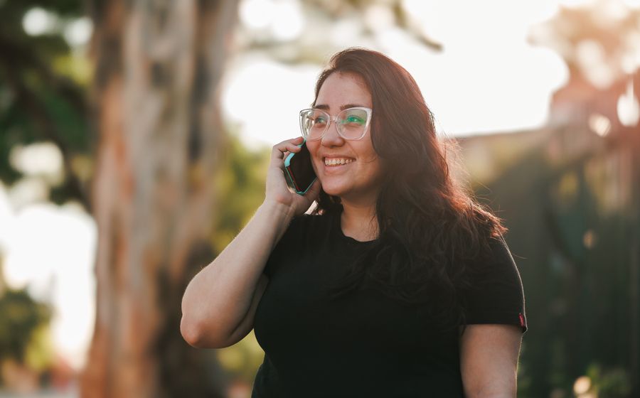 A woman smiling while talking on the phone outdoors