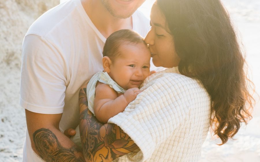 Young parents laughing while holding their baby daughter