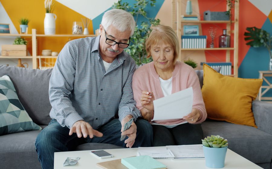 An older couple going over their budget together on the sofa