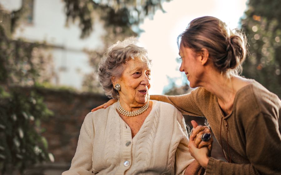 An older woman and her adult daughter talking in the garden